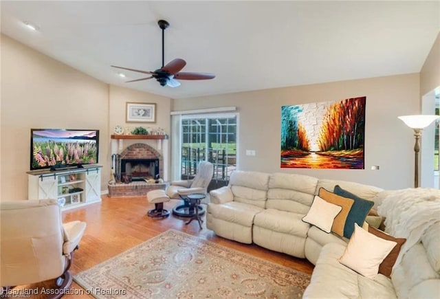 living room with a brick fireplace, light hardwood / wood-style flooring, ceiling fan, and lofted ceiling