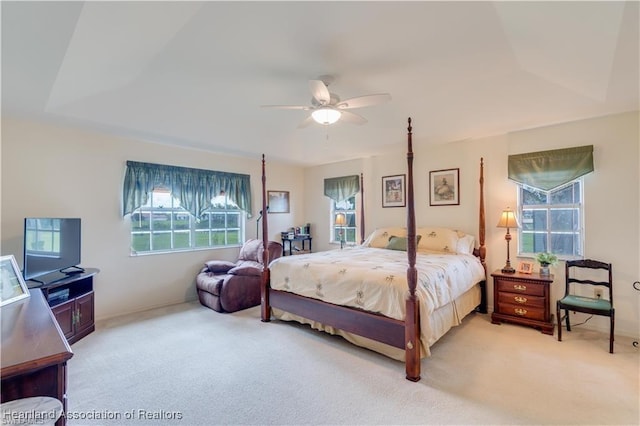 bedroom with ceiling fan, carpet floors, and a tray ceiling