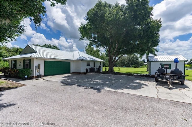 view of front of home featuring a garage, central air condition unit, and a front yard