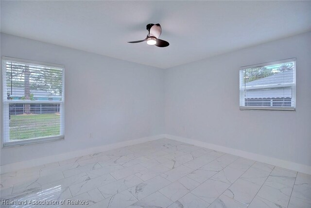 spare room featuring ceiling fan and a healthy amount of sunlight