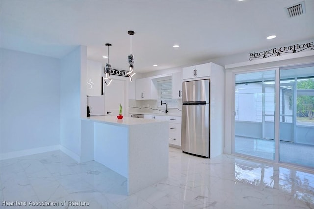 kitchen featuring kitchen peninsula, appliances with stainless steel finishes, sink, decorative light fixtures, and white cabinetry