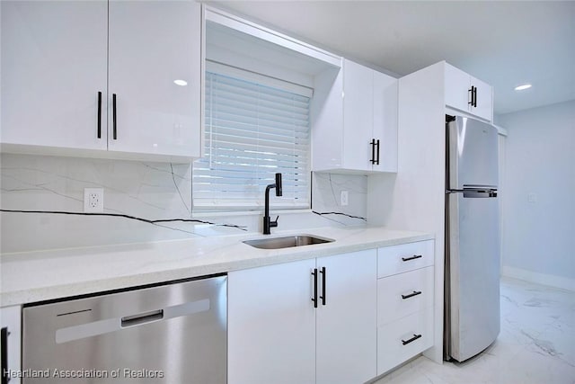 kitchen with white cabinets, appliances with stainless steel finishes, light stone counters, and sink