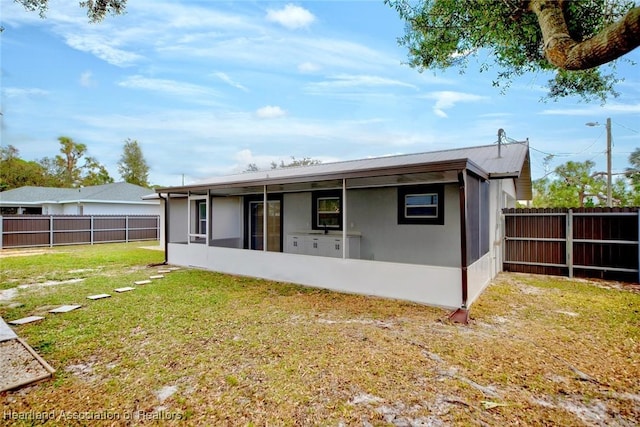 rear view of property with a sunroom and a lawn