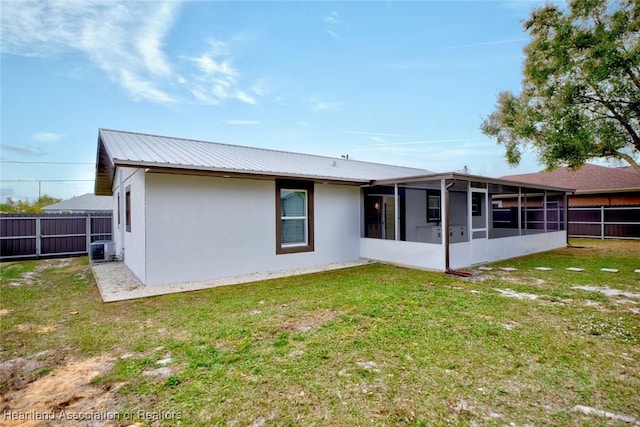 rear view of property with a lawn, a sunroom, and central AC