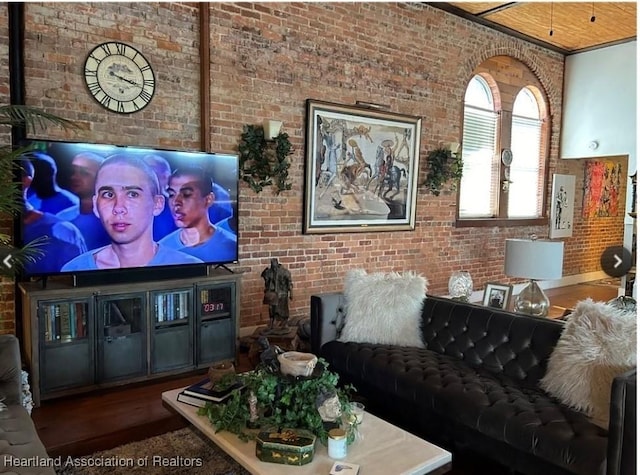 living room with brick wall and dark hardwood / wood-style flooring