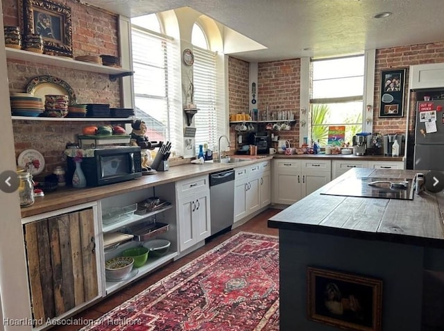 kitchen featuring sink, brick wall, black appliances, a textured ceiling, and white cabinets