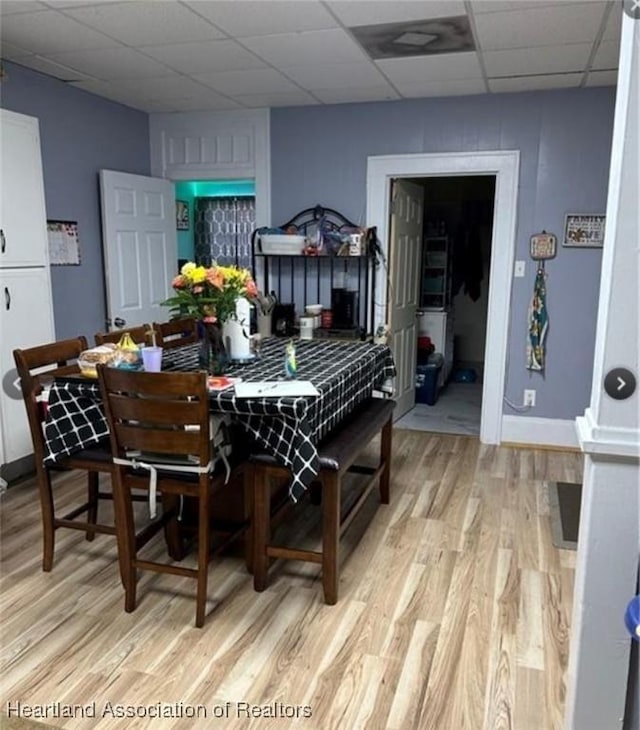 dining area featuring a paneled ceiling and light wood-type flooring