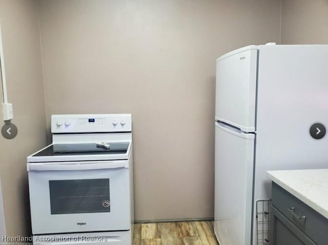 kitchen with white appliances, gray cabinets, and light hardwood / wood-style floors