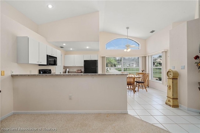 kitchen with hanging light fixtures, light tile patterned floors, kitchen peninsula, white cabinets, and black appliances