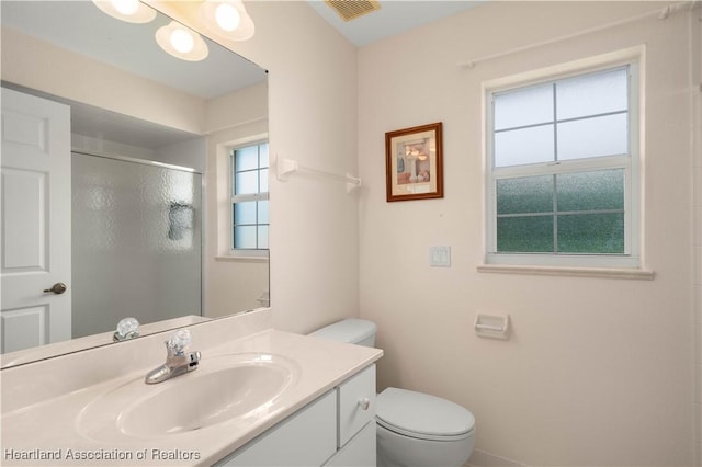 bathroom featuring vanity, toilet, and a shower with door