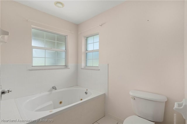 bathroom featuring tile patterned flooring, a washtub, and toilet