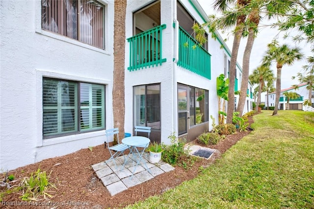 rear view of house with a balcony and a yard