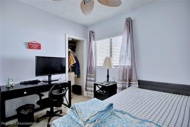 tiled bedroom featuring ceiling fan, a spacious closet, a textured ceiling, and a closet