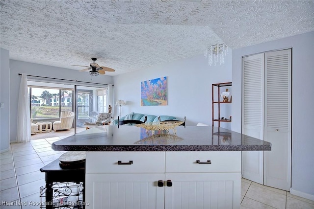 kitchen featuring white cabinetry, a center island, light tile patterned floors, ceiling fan, and a textured ceiling