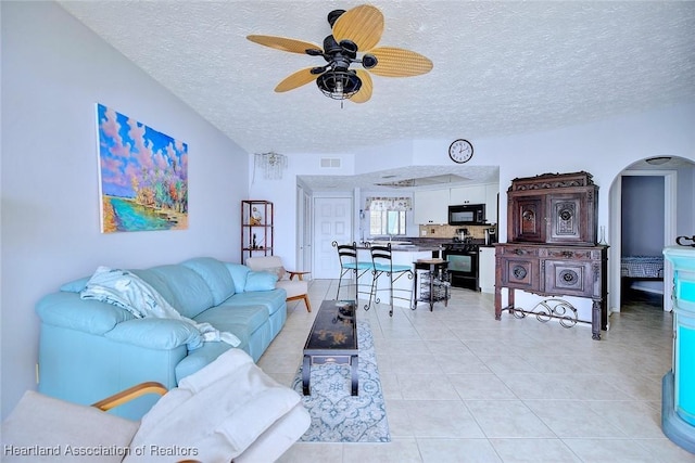 tiled living room featuring ceiling fan and a textured ceiling