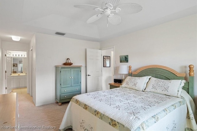 bedroom with connected bathroom, a raised ceiling, and ceiling fan