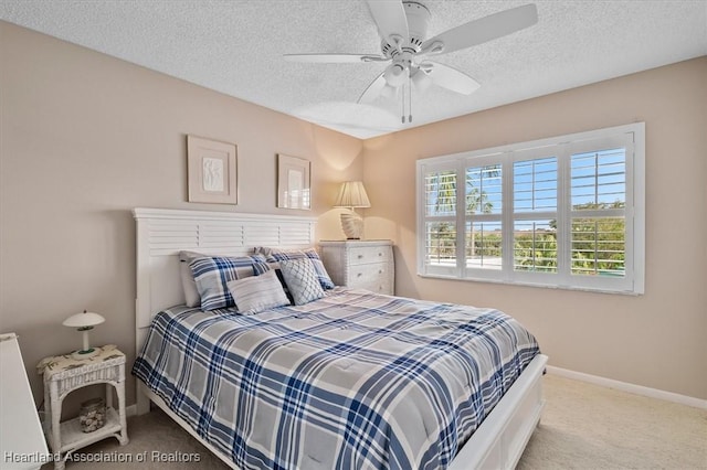 bedroom featuring ceiling fan, light carpet, and a textured ceiling