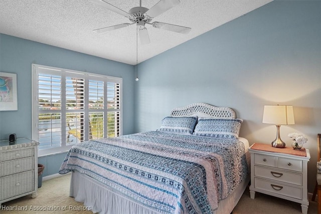 bedroom featuring ceiling fan, light colored carpet, and a textured ceiling