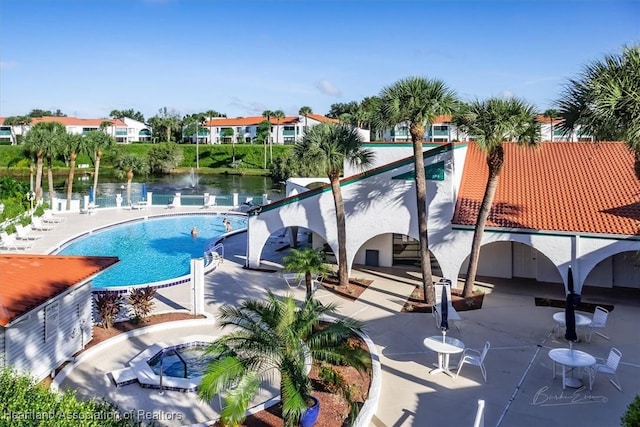 view of pool with a water view and a patio