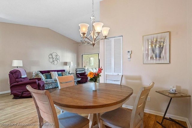 dining area with light hardwood / wood-style floors, lofted ceiling, and a notable chandelier