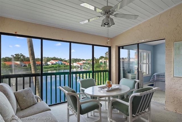 sunroom featuring ceiling fan, a water view, wooden ceiling, and lofted ceiling