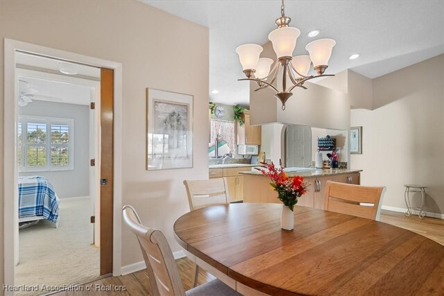 dining area with sink, light hardwood / wood-style floors, and ceiling fan with notable chandelier