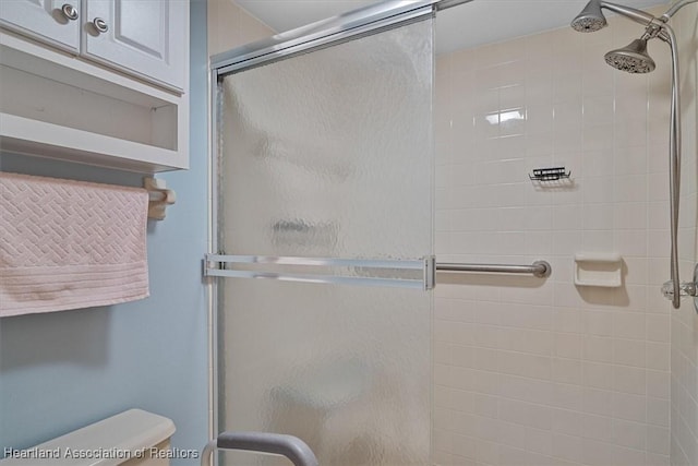 bathroom with toilet and a shower with door