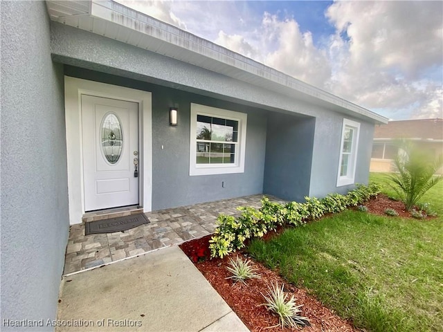 view of exterior entry featuring covered porch and stucco siding