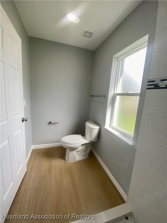 bathroom with visible vents, toilet, baseboards, and wood finished floors