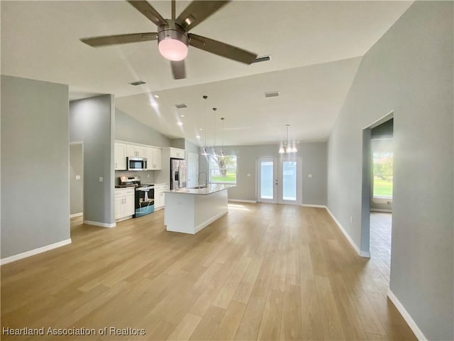 kitchen featuring light wood finished floors, open floor plan, white cabinets, and appliances with stainless steel finishes