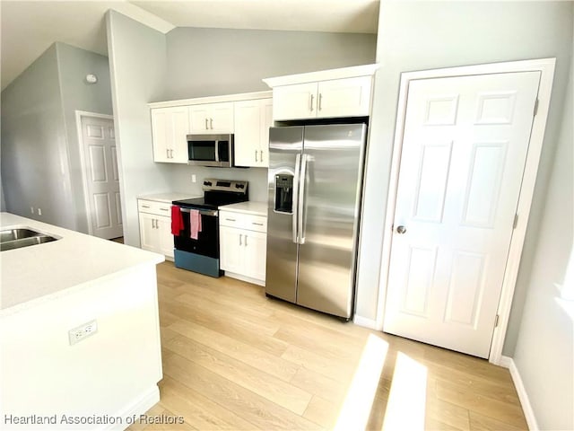 kitchen featuring appliances with stainless steel finishes, white cabinets, light countertops, and light wood finished floors