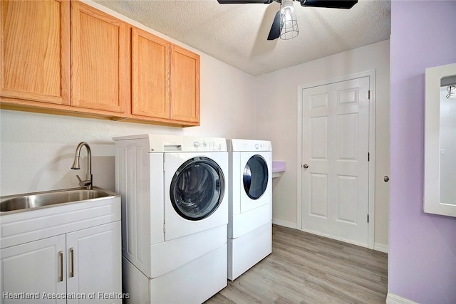 laundry area featuring washing machine and clothes dryer, a textured ceiling, light wood-type flooring, and sink