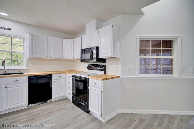 kitchen with black appliances, wood counters, white cabinetry, and sink