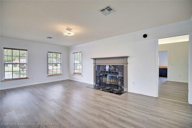 unfurnished living room with a high end fireplace, hardwood / wood-style floors, a textured ceiling, and ornamental molding