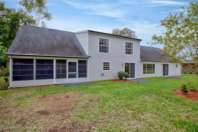 back of property featuring a sunroom and a lawn