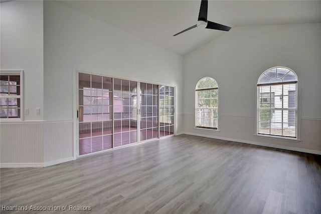 spare room with ceiling fan, high vaulted ceiling, and wood-type flooring