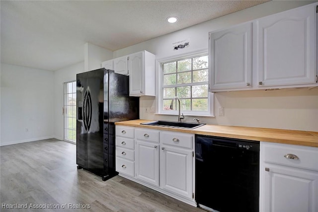 kitchen with white cabinetry, sink, black appliances, and wood counters