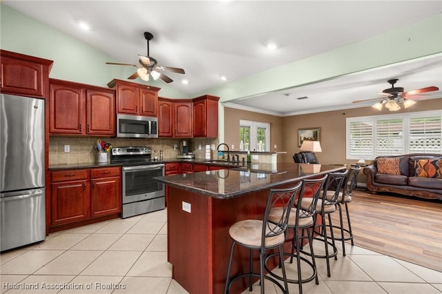 4023 Santa Barbara Dr, Sebring, FL 33875 - kitchen with appliances with stainless steel finishes, a ceiling fan, a kitchen bar, light tile patterned flooring, and crown molding