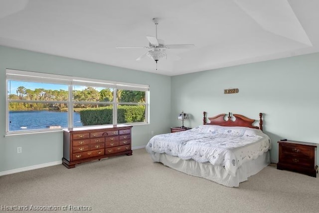 carpeted bedroom featuring a water view and ceiling fan