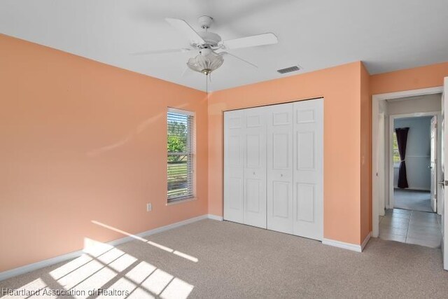 unfurnished bedroom with carpet, ceiling fan, and a closet