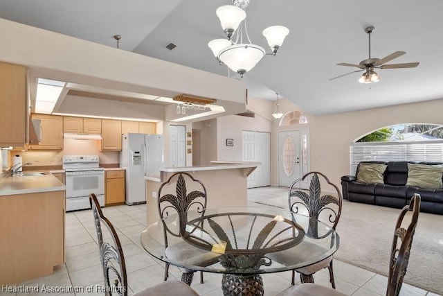 tiled dining area with sink, ceiling fan with notable chandelier, and vaulted ceiling