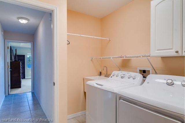 laundry room featuring washing machine and clothes dryer, sink, light tile patterned floors, and cabinets