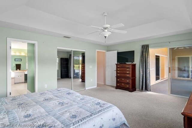 bedroom with ceiling fan, a closet, light carpet, and ensuite bath