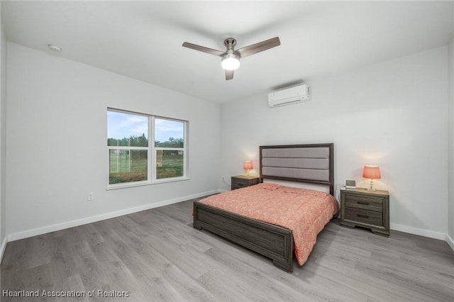 bedroom featuring ceiling fan, light hardwood / wood-style floors, and a wall mounted air conditioner