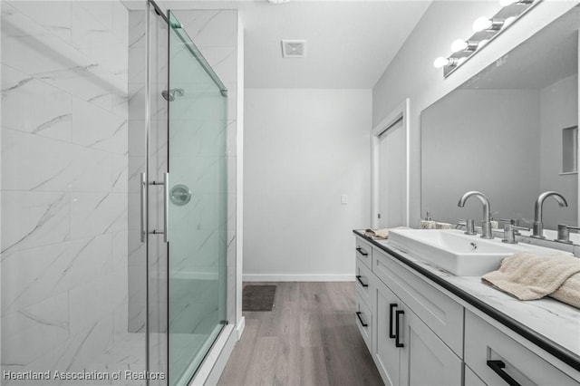 bathroom with a shower with shower door, hardwood / wood-style floors, and vanity