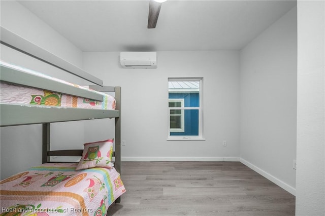 bedroom featuring ceiling fan, an AC wall unit, and hardwood / wood-style flooring