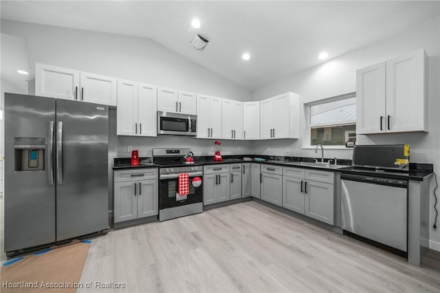 kitchen featuring gray cabinetry, sink, light wood-type flooring, stainless steel appliances, and lofted ceiling