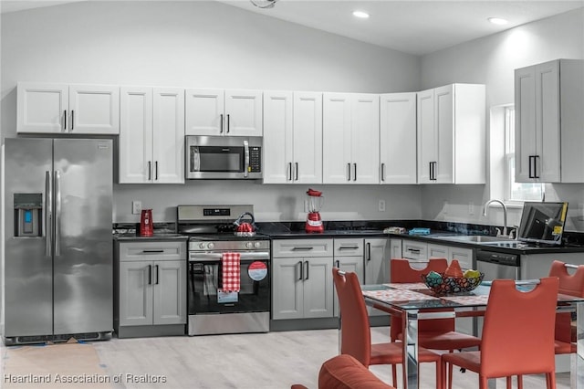 kitchen with sink, appliances with stainless steel finishes, and vaulted ceiling