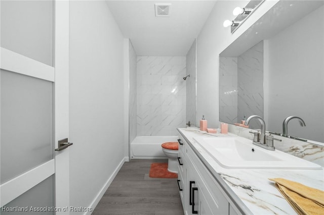 full bathroom featuring hardwood / wood-style flooring, toilet, vanity, and tiled shower / bath