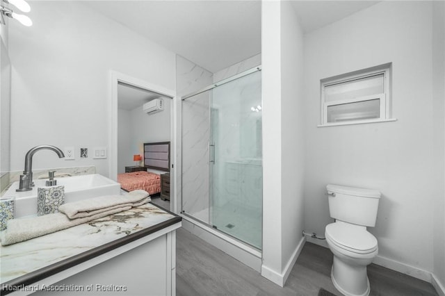 bathroom featuring wood-type flooring, vanity, toilet, a shower with shower door, and a wall mounted air conditioner